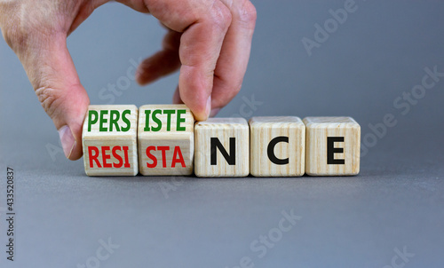 Persistence or resistance symbol. Businessman turns cubes, changes the word 'resistance' to 'persistence'. Beautiful grey background. Copy space. Business and persistence or resistance concept.