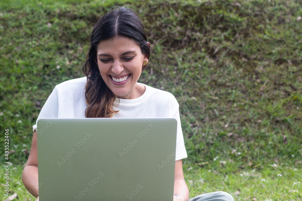 latina woman smiling at laptop in an online class. latina woman smiling at laptop in an online class.