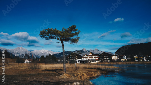 Paese di montagna italiano con lago, albero e case
