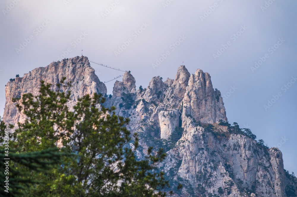 Naklejka premium High rocky mountains with forested slopes and peaks hidden in the clouds. Ai-Petri, Crimea