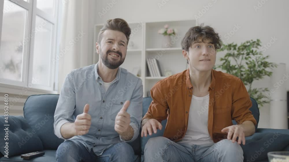 Slow-mo of two happy men watching sport match on tv, emotionally supporting team Slow-mo of two happy men watching sport match on tv, emotionally supporting team