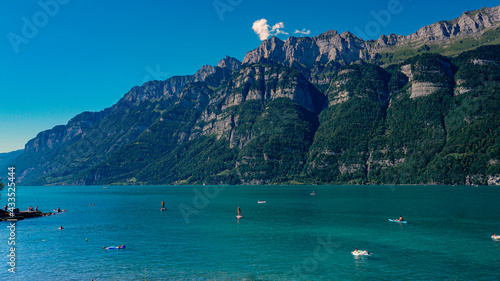 Stunning turquoise alpine water mountain lake in Switzerland, with Swiss alps in background with people enjoying vacation holidays time
