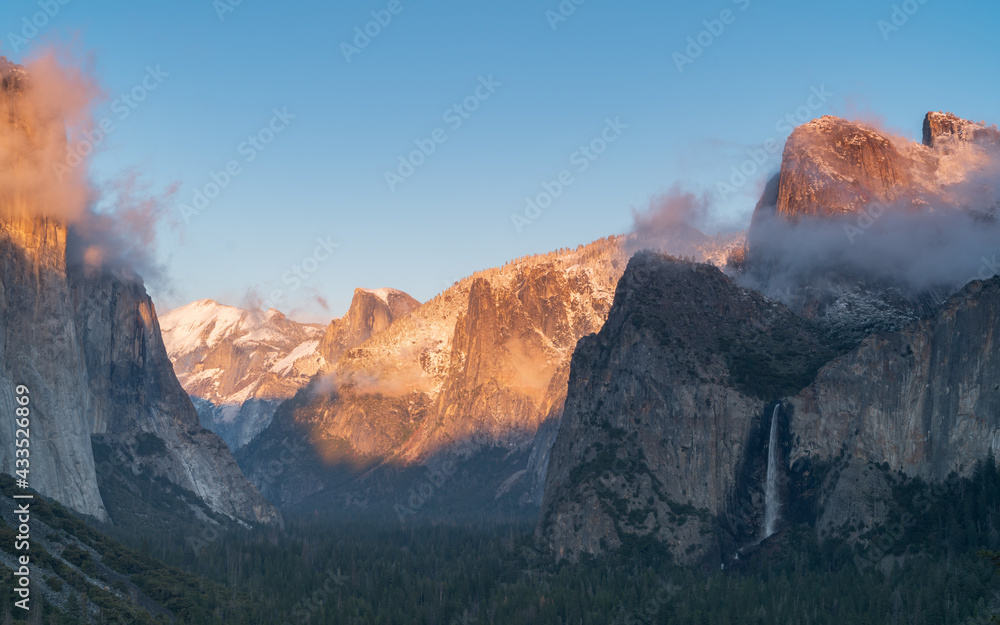 winter sunset shot of snow on yosemite's half dome as storm clouds clear from yosemite national park