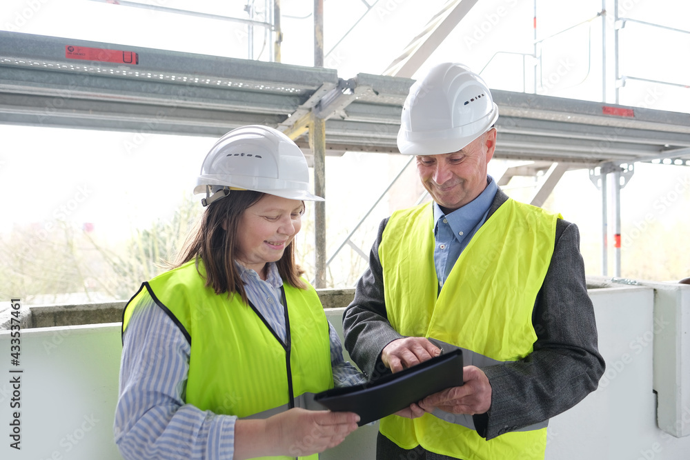 experienced elderly architect, female engineer constructor in protection of white helmet accept the object, sign documents at construction site, concept of civil engineering, cooperation experienced elderly architect, female engineer constructor in protection of white helmet accept the object, sign documents at construction site, concept of civil engineering, cooperation