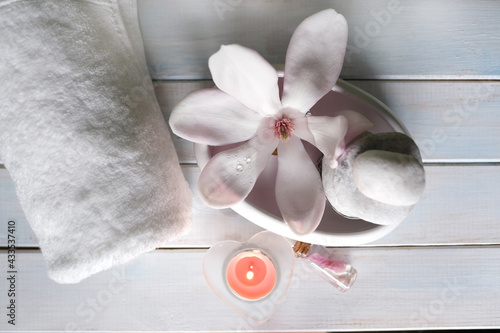 Fototapeta Naklejka Na Ścianę i Meble -  beautiful pink magnolia flower, smooth white stones in a stack, candles, white towel, concept of wellness spa treatments for the beauty of body and soul, massage, zen stone in the pool of serenity