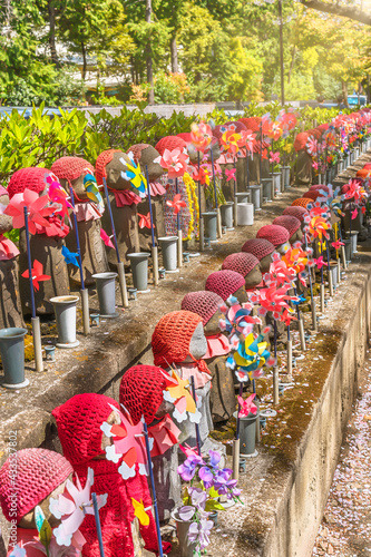 Thousand statues of Kosodate Jizo bodhisattva symbol of filial piety to protect children depicted with a red knit cap and bib and pinwheels in the Buddhist Zojoji temple. photo