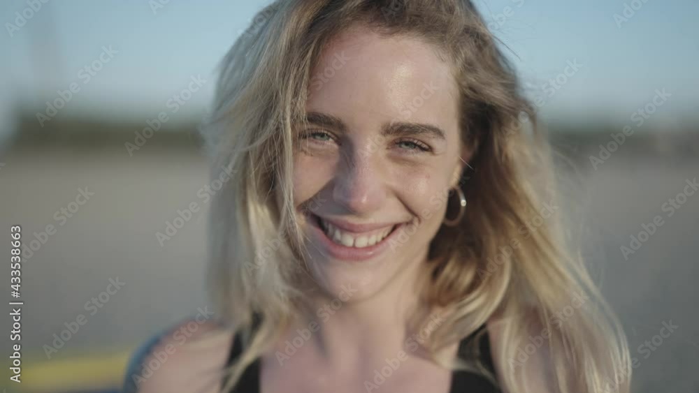 Portrait of an attractive blond young woman looks at the camera and smiles and laughing happily at the beach.
Portrait of an attractive blond young woman looks at the camera and smiles and laughing happily at the beach.