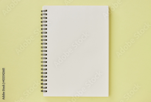 Spiral Notebook or Spring Notebook in Unlined Type on Pastel Yellow Minimalist Background. Spiral Notebook Mock up on Center Frame