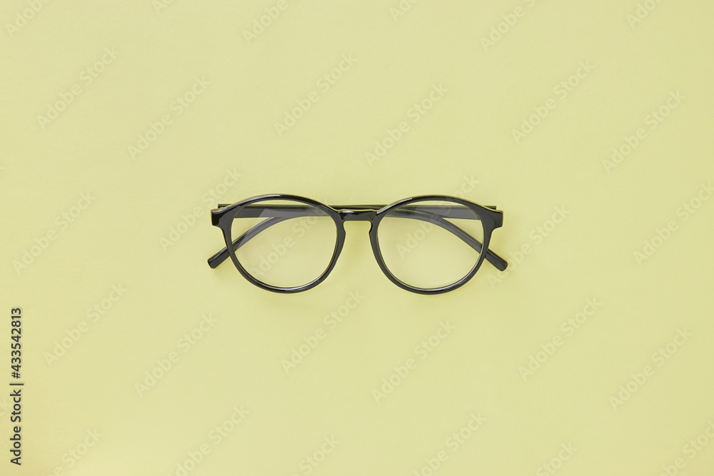 Top View Black Glasses on Pastel Yellow Minimalist Background Top View Black Glasses on Pastel Yellow Minimalist Background
