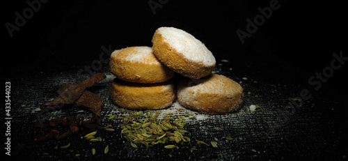 Closeup of a Home Made Baked Wheat Cookies or Biscuits stacked in a isolated black background. Flavor of Cinnamon, Fennel seeds, clove and sprinkle of Sugar Powder. Bakery. Pastry. Food Photography