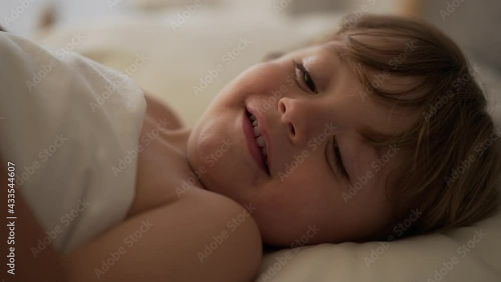 Beautiful baby toddler smiling under bed sheets in the morning Beautiful baby toddler smiling under bed sheets in the morning