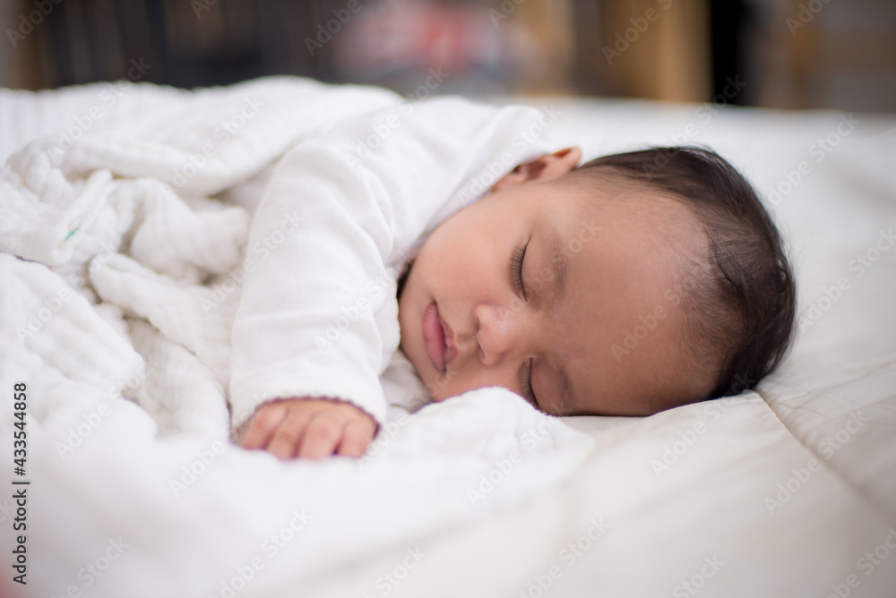 Infants are looking forward in an upside-down position on a white bed, the evolution of Baby girl in the age up to 6 months./Selected focus Infants are looking forward in an upside-down position on a white bed, the evolution of Baby girl in the age up to 6 months./Selected focus