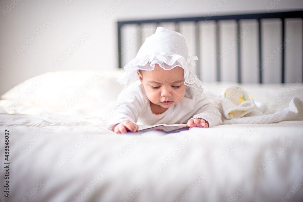 Infants are looking forward in an upside-down position on a white bed, the evolution of Baby girl in the age up to 6 months./Selected focus Infants are looking forward in an upside-down position on a white bed, the evolution of Baby girl in the age up to 6 months./Selected focus