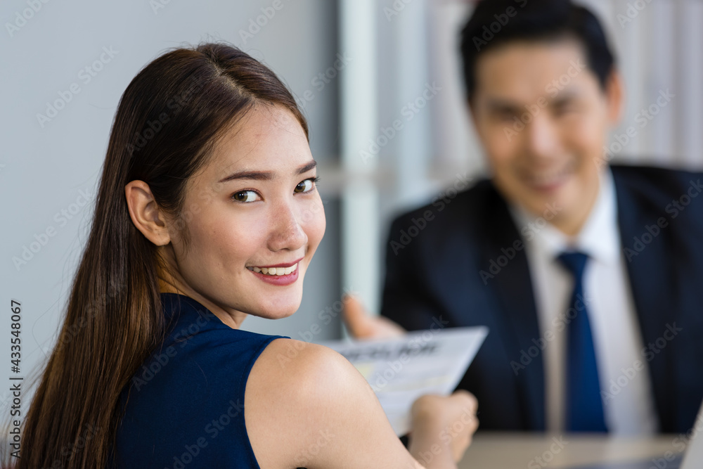 Young Asian man and woman smiling while sitting at table during job interview Young Asian man and woman smiling while sitting at table during job interview