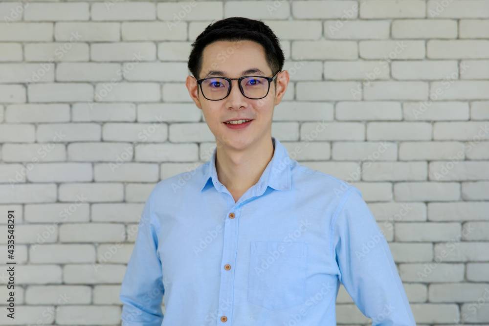 Authentic photo taken with natural light of young and handsome Asian man wearing eyeglasses pose with self-confidence and friendly to camera on brick wall background Authentic photo taken with natural light of young and handsome Asian man wearing eyeglasses pose with self-confidence and friendly to camera on brick wall background