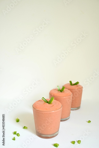 three glass glasses with creamy spanish cordobes salmorejo gazpacho with green pepper topping on surface and white background