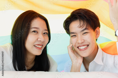 LGBTQ couple lovers, a handsome girl as a man or butch femme covered .with the rainbow flag the symbol of LGBT, spending and sharing loving time with fun, warmth, and happiness photo