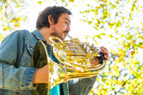 Canvas Print low angle view of a musician playing the french horn in the park practicing