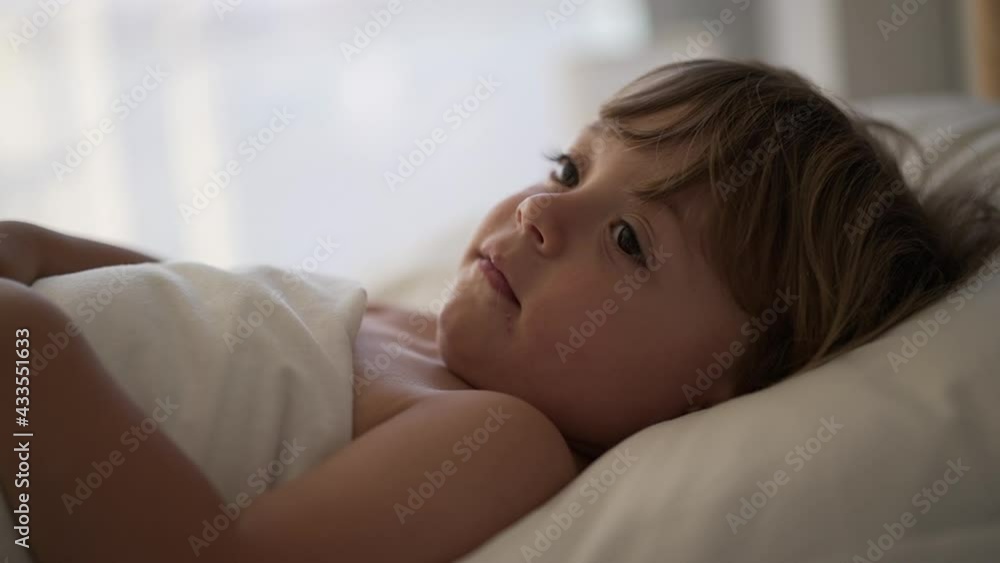 Calm little baby toddler under bed sheets in the morning, blond child boy Calm little baby toddler under bed sheets in the morning, blond child boy