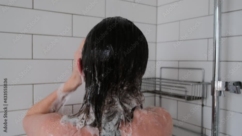 Woman washes hair under water jets in shower unit at home Woman washes hair under water jets in shower unit at home