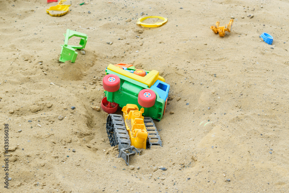 Toy dump trucks, a tractor in a sand quarry. The concept of a children's sandbox with toys. Toy dump trucks, a tractor in a sand quarry. The concept of a children's sandbox with toys.