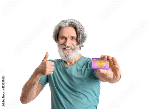 Senior man with gift card showing thumb-up on white background