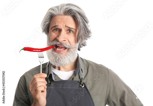 Senior man eating chili pep...