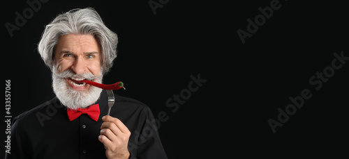 Senior man eating chili pep...