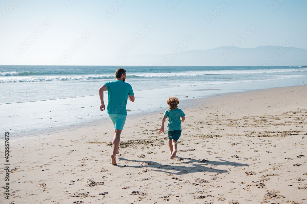 Father and son running on sea. Dad and child having fun outdoors. Family travel, vacation, father's day concept.