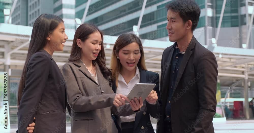 A team of business partners are standing outdoors and discussing an upcoming project using laptop. A group of male and female corporate/ office employees are interacting outside commercial complex A team of business partners are standing outdoors and discussing an upcoming project using laptop. A group of male and female corporate/ office employees are interacting outside commercial complex