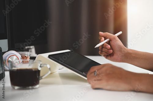 Close up view businessman holding stylus pen and digital tablet while sitting at home office. photo