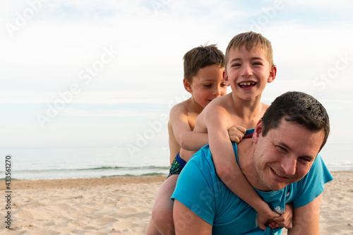 Father and his two sons laughing on the beach.
