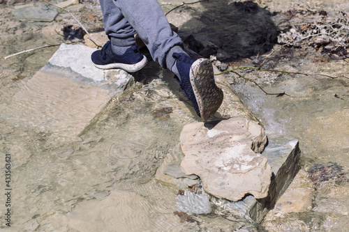 Close-up of the legs of an unrecognizable person in hiking shoes on the rocks. Male hiking in the summer mountains.