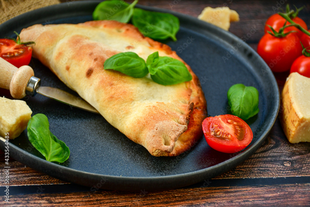 Home made italian calzone vegetarian pizza with tomatoes, mozzarella and parmesan cheese and fresh basil Home made italian calzone vegetarian pizza with tomatoes, mozzarella and parmesan cheese and fresh basil