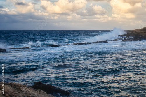 Water crashing over a line of rocks in the ocean at Qawra  Malta on a fall evening.