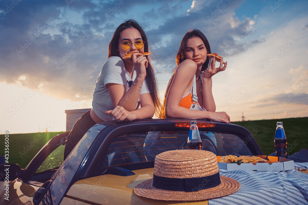 Charming girls eating pizza, posing in yellow car roadster with french  fries, hat and soda in glass bottles on trunk. Fast food. Mock up Photos |  Adobe Stock