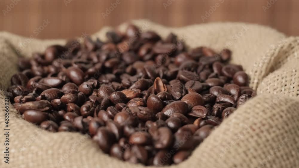 From above, dark coffee beans fall into an eco-bag made of burlap. Natural coffee. 4k video. From above, dark coffee beans fall into an eco-bag made of burlap. Natural coffee. 4k video.