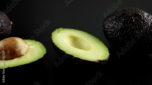 Wallpaper Mural Halved avocado with a stone and two whole ripe avocados on a black background, 4K UHD dolly side pan  Torontodigital.ca