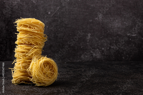 Capellini spaghetti on a dark structural background with space to copy. Spaghetti stacked in a tower