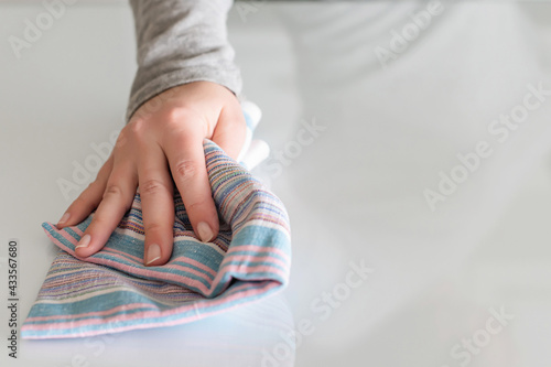 Cleaning wipe with a cloth in the hands of woman kitchen table. Housekeeping service. The concept of disinfection. Protection from viruses and bacteria