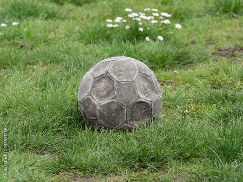 Old weathered leather football is flat and lies in the grass © Farantsa