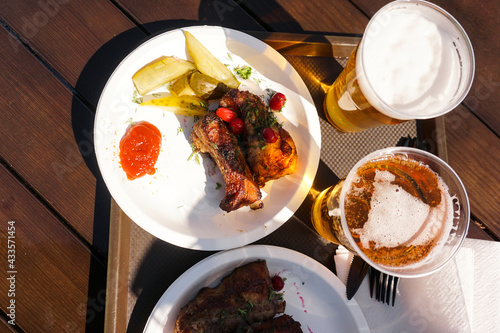 Fototapeta Naklejka Na Ścianę i Meble -  Pork ribs on a tray and light beer on wooden table background. Street food. Festival food on a sunny day