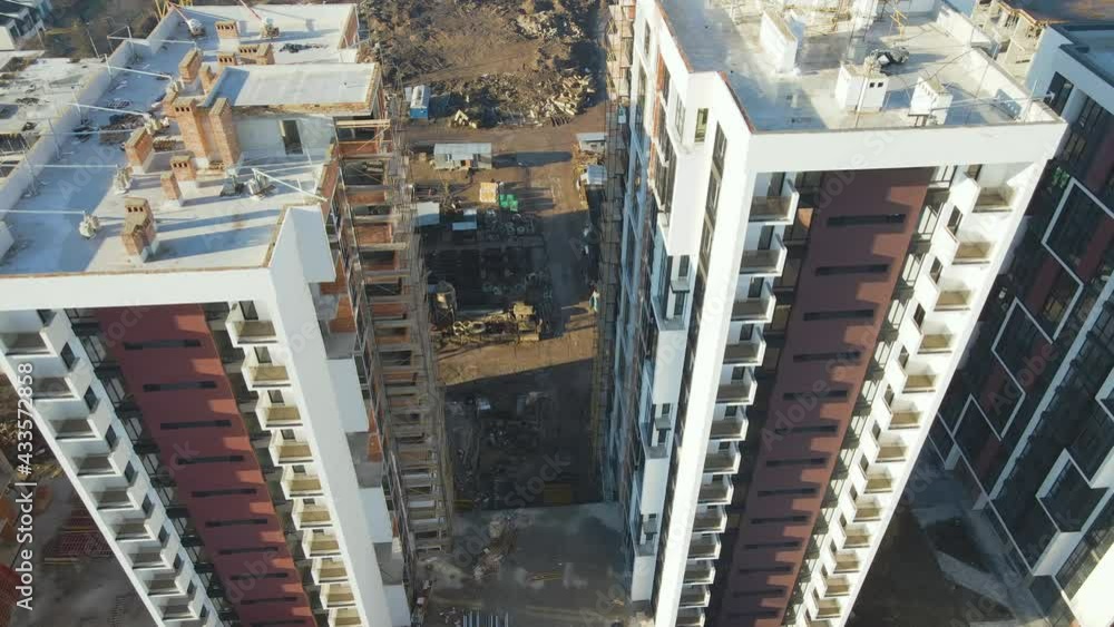Aerial view of high tower crane and residential apartment buildings under construction. Real estate development. Aerial view of high tower crane and residential apartment buildings under construction. Real estate development.
