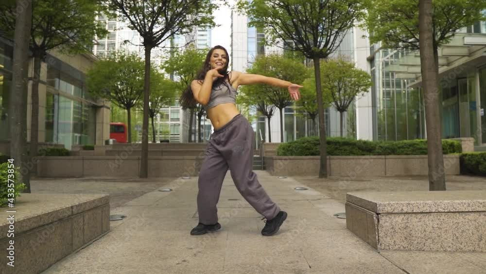 Skilled female hip hop dancer performing various of styles mixed together in a park near to metropolis city environment energetic positive attitude great charisma iconic movements Skilled female hip hop dancer performing various of styles mixed together in a park near to metropolis city environment energetic positive attitude great charisma iconic movements