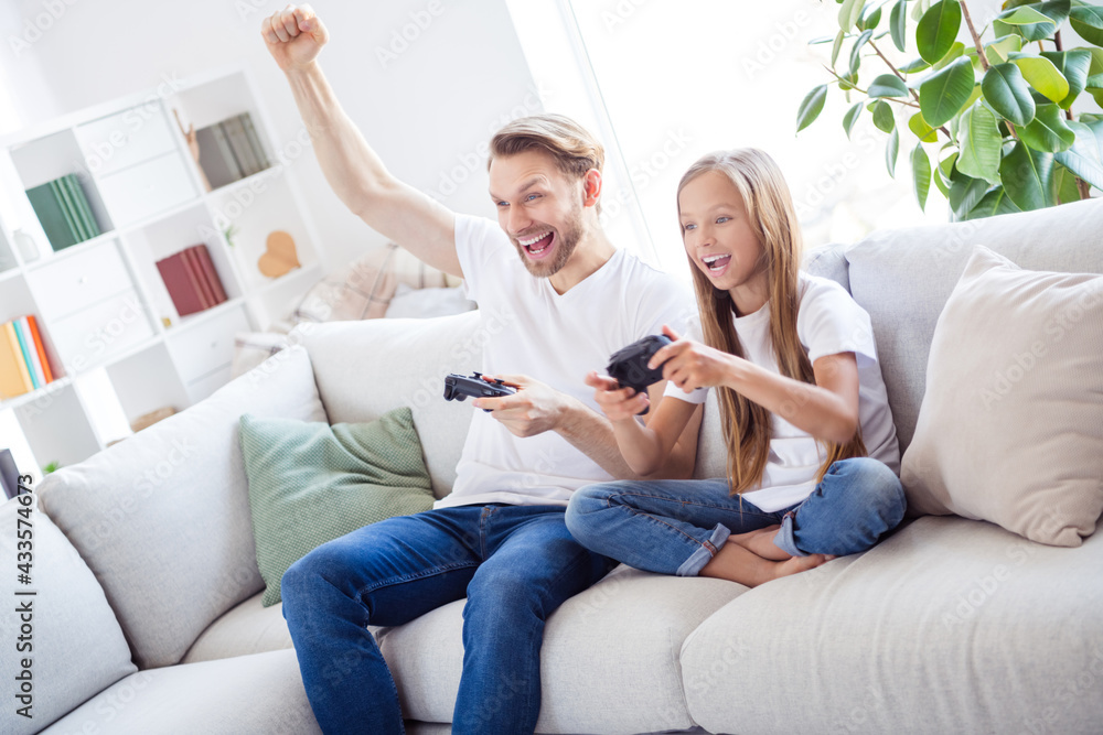 Photo of sweet funky father daughter dressed casual clothes sitting couch having playstation game competition indoors house apartment Photo of sweet funky father daughter dressed casual clothes sitting couch having playstation game competition indoors house apartment