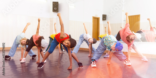 Group of children in casual clothes training hip-hop in class, learning modern dance movements photo