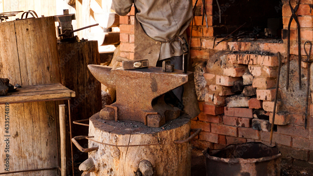 A blacksmith in an authentic workshop. Blacksmithing in the village. Focus on the metal anvil