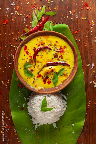 Close-up of Indian cooked rice with kadi or kadhi over the banana fresh green leaf. Garnished with curry-patta leaves and red chilli paper and salt. photo