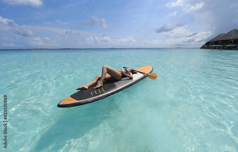 girl in bikini lies on Surfboard in the ocean, Maldives