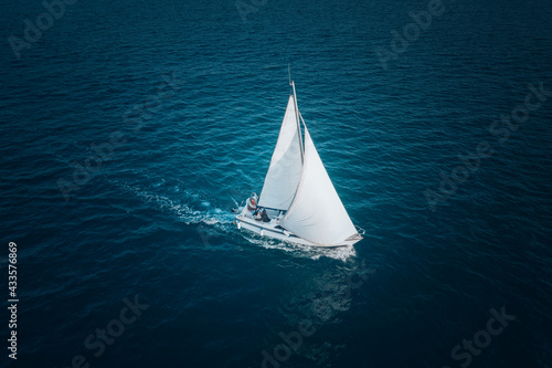Regatta sailing ship yachts with white sails at opened sea. Aerial view of sailboat in windy condition. © ValentinValkov